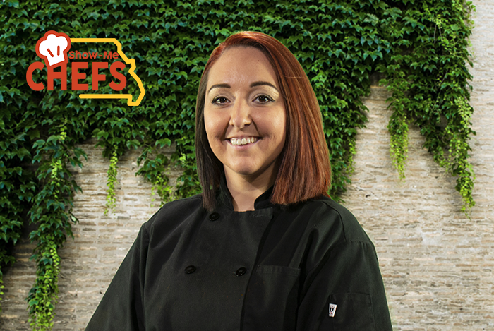 Chef Jessica Owens smiles in front of a brick wall covered in ivy