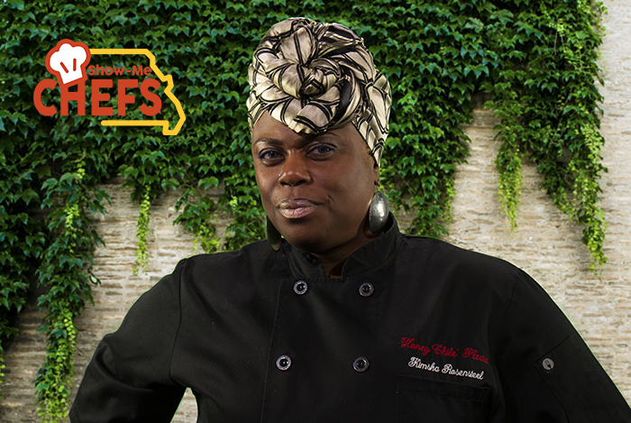 Chef Kimsha smiles in front of a brick wall covered in ivy