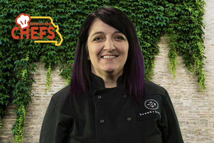 Chef Lorelei Morris smiles in front of a brick wall covered in ivy
