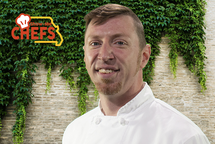Chef Marty Lowry smiles in front of a brick wall covered in ivy.