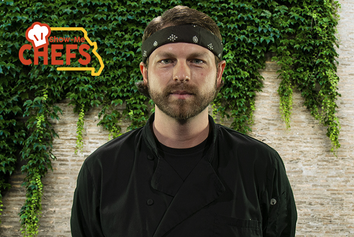 Chef Zach shows off his game face in front of a brick wall covered in ivy