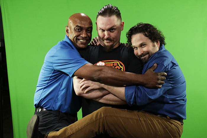 Angelo, Joey, and Nathan goof off and hug in front of a green screen on promo day
